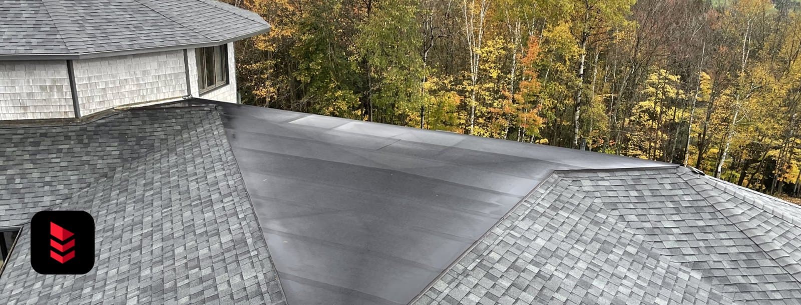 Close aerial view of an asphalt shingle roof with a rubber low-slope section